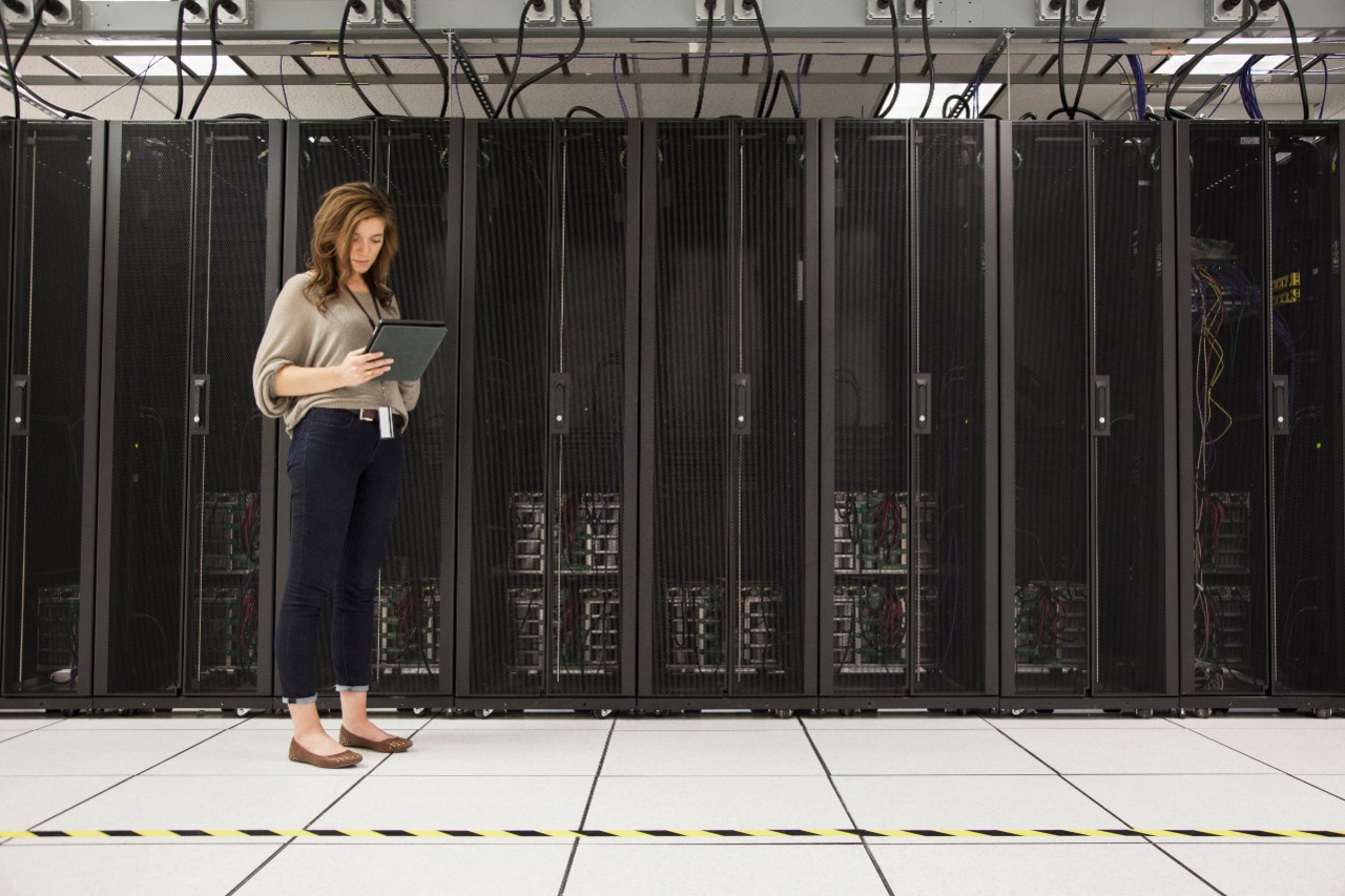 Mixed race businesswoman using tablet computer in server room